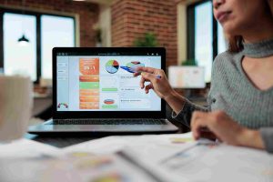 A woman sitting at a desk, focused on a laptop while browsing a website.